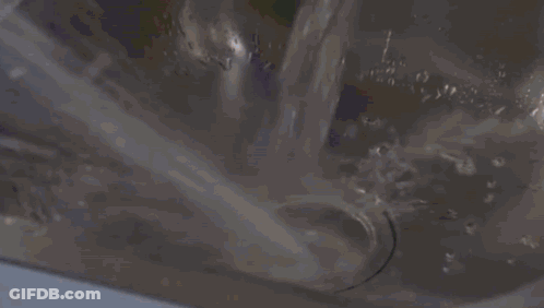 Woman In Yellow Hat And Blue Raincoat In Kitchen GIF
