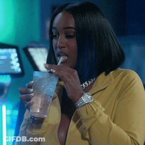Woman In Yellow Jacket Drinking From Glass With Straw GIF