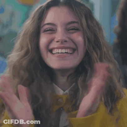 Woman In Yellow Jacket Laughing With Hands Up GIF