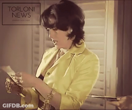Woman In Yellow Jacket Reads Torloni News GIF
