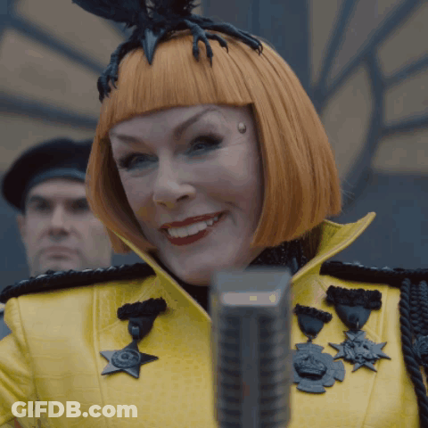 Woman In Yellow Jacket With Medals Smiling At Microphone GIF