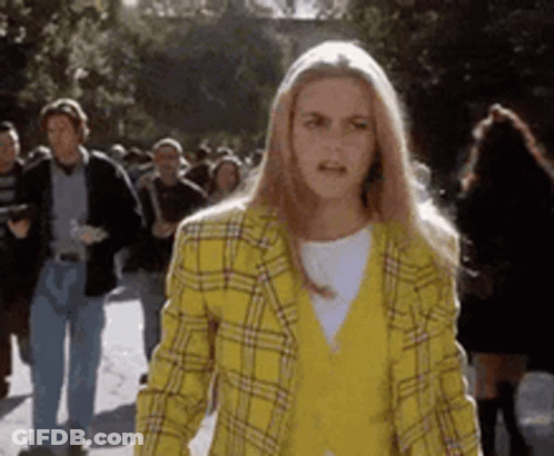 Woman In Yellow Plaid Jacket Walking Down Street GIF