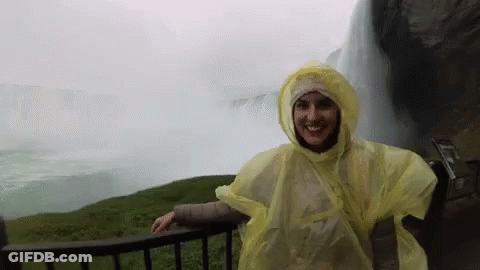 Woman In Yellow Poncho By Waterfall GIF