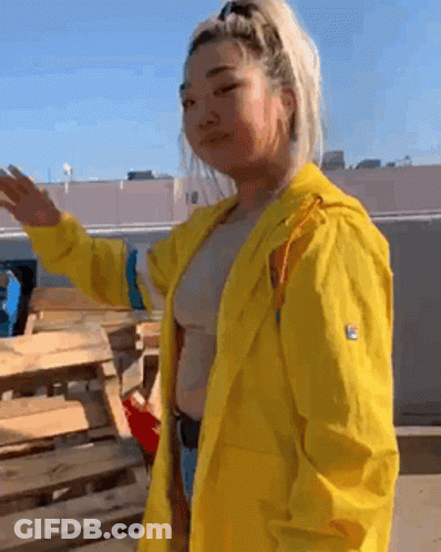 Woman In Yellow Raincoat By Wooden Pallet GIF