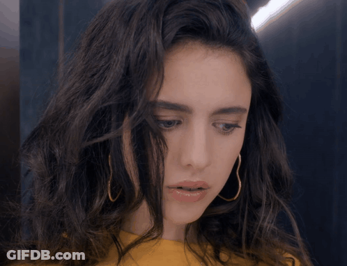 Woman In Yellow Shirt And Gold Hoop Earrings Looking Down GIF