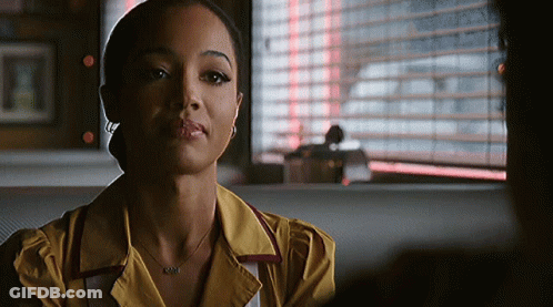 Woman In Yellow Shirt And Necklace Sitting In Diner GIF