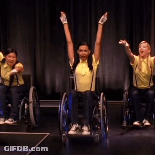 Woman In Yellow Shirt And Suspenders In Wheelchair GIF