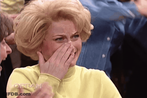 Woman In Yellow Shirt Covering Mouth With Oprah Behind GIF
