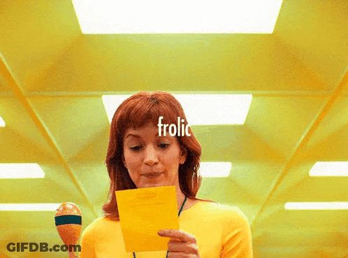 Woman In Yellow Shirt Holding Paper Saying Frolic GIF