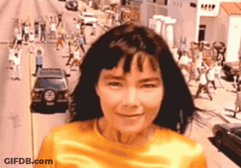 Woman In Yellow Shirt Smiling In Crowd GIF