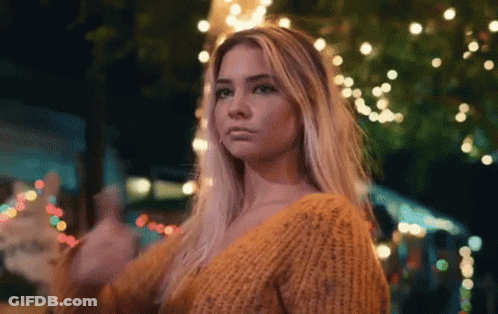 Woman In Yellow Sweater In Front Of Christmas Tree At Night GIF