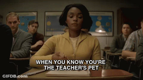 Woman In Yellow Sweater Sitting At Classroom Desk GIF