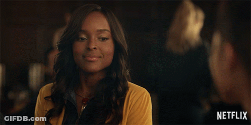 Woman In Yellow Sweater Smiling In Front Of Netflix Logo GIF