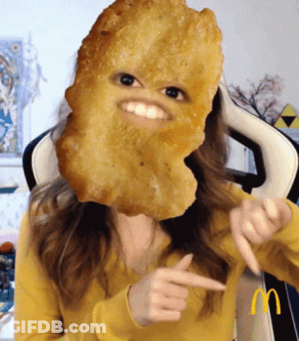 Woman In Yellow Sweater With Chicken Nugget On Face GIF