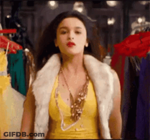 Woman In Yellow Top And Fur Vest By Closet GIF