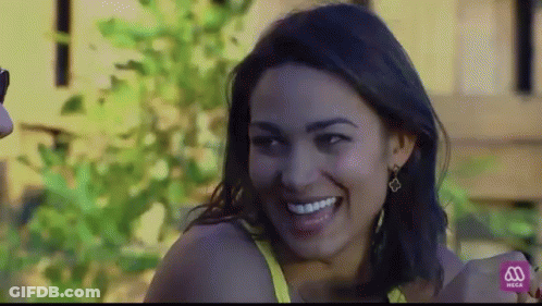 Woman In Yellow Top Smiling In Front Of Mega Sign GIF