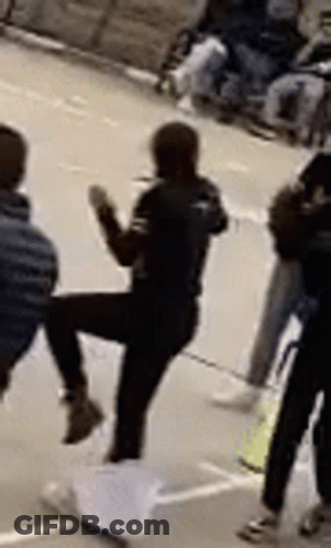 Woman Kicking Man In Front Of Group GIF
