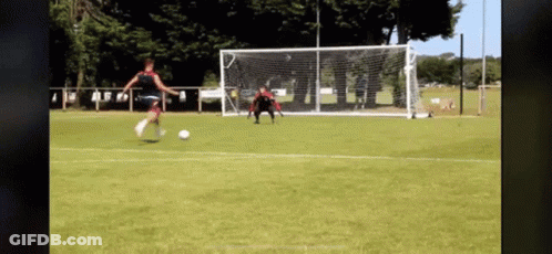 Woman Kicking Soccer Ball Into Goal With Goalie GIF