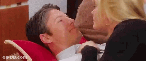 Woman Kissing Man On Cheek While He Lays On Pillow GIF