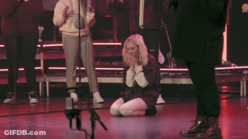 Woman Kneeling Before Microphone With Folded Hands GIF