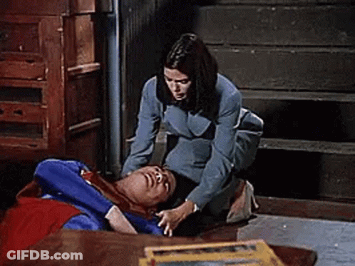 Woman Kneeling Beside Man In Superman Costume On Floor GIF
