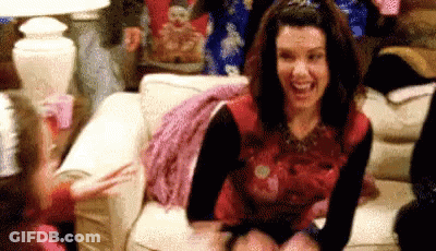 Woman Laughing And Waving On Couch GIF