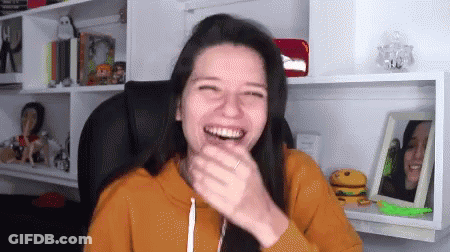 Woman Laughing In Chair By Bookshelf GIF