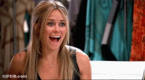 Woman Laughing With Mouth Open Beside Clothes Rack GIF