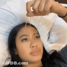 Woman Laying In Bed Holding Necklace GIF