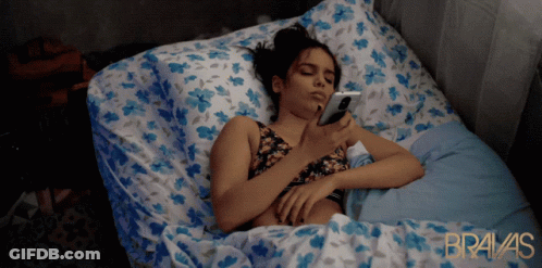 Woman Laying In Bed On Phone Bravas In Gold GIF