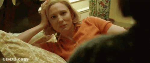 Woman Laying On Bed Hand On Forehead Looking At Camera GIF