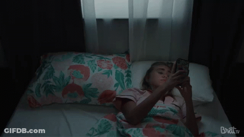 Woman Laying On Bed Looking At Phone Brat TV GIF