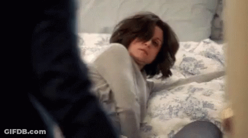 Woman Laying On Bed With Man Behind GIF