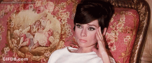 Woman Laying On Couch Hand On Forehead Floral Rug GIF