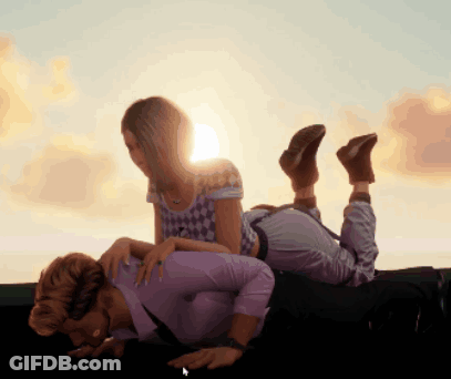Woman Laying On Man's Lap With Sun Behind Them GIF