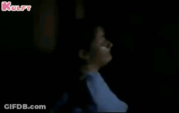Woman Leaning Against Pole In Dark GIF
