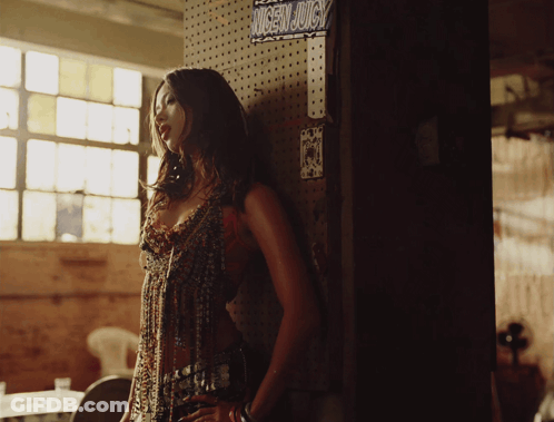 Woman Leaning Against Wall Next To Juice Sign GIF