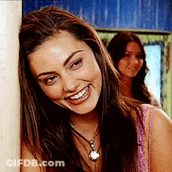 Woman Leaning Against Wall Smiling With Necklace GIF
