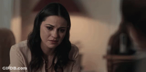 Woman Looking At Camera With Man In Background GIF