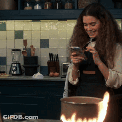 Woman Looking At Cell Phone In Kitchen GIF