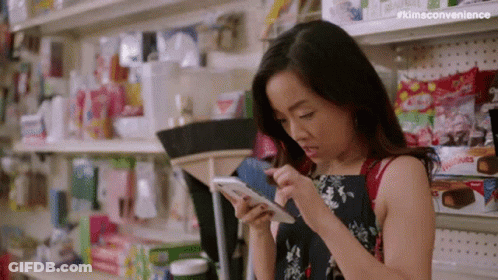 Woman Looking At Cell Phone In Store Aisle GIF