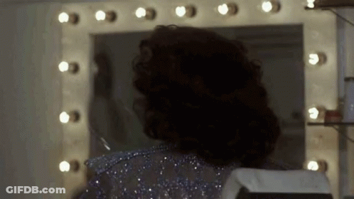 Woman Looking At Herself In Mirror With Lights GIF
