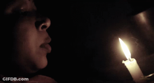 Woman Looking At Lit Candle In Darkness GIF