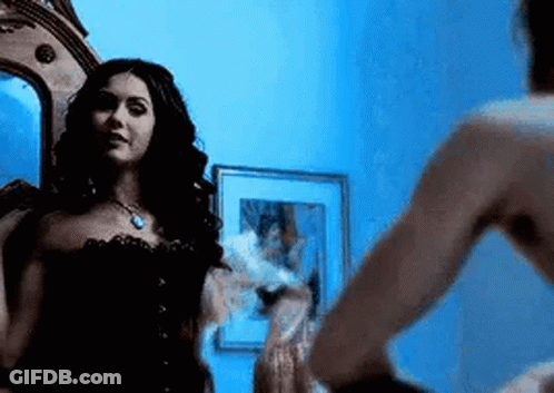 Woman Looking In Mirror With Man Standing Next To Her GIF