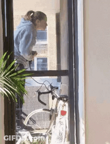 Woman Looking Out Window At Bike GIF