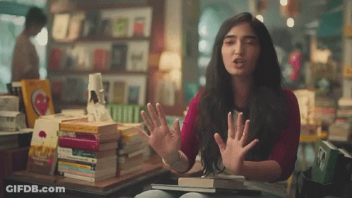 Woman Making Funny Face In Front Of Books GIF