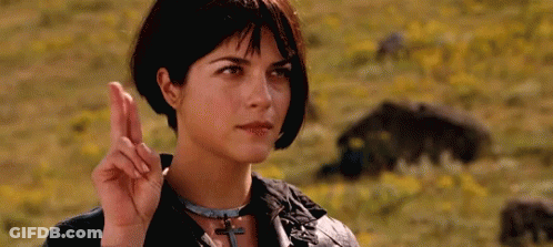 Woman Making Peace Sign In A Field Of Flowers GIF