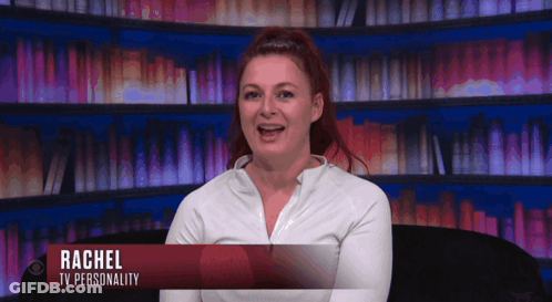 Woman Named Rachel Sits In Front Of Bookshelf GIF