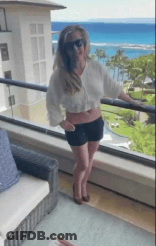Woman On Balcony Looking Over Ocean GIF