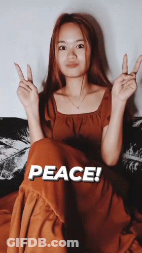 Woman On Couch Giving Peace Sign Saying Peace GIF